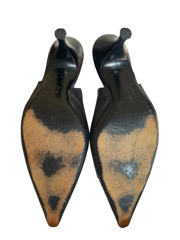 A pair of pointed-toe kitten heels shown from the sole, featuring a glossy black upper and a heavily worn, scuffed tan-brown leather outsole against a plain white background.