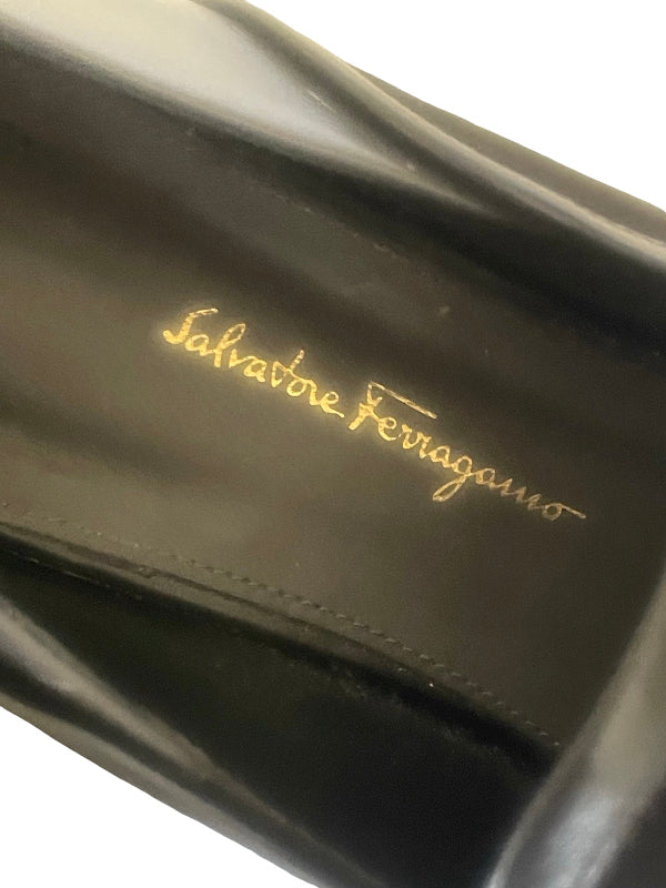 Close-up of a black leather Salvatore Ferragamo shoe interior with gold script branding on a white background.