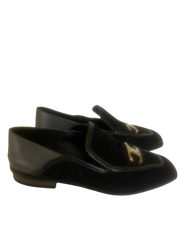 A pair of black suede and leather mule loafers with a silver  interlocking CC logo on the vamp, characteristic of Salvatore Ferragamo, shown against a plain white background.