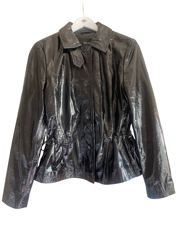 A shiny black leather jacket with a pointed collar, button front, and gathered peplum waist, hanging on a white hanger against a white background.