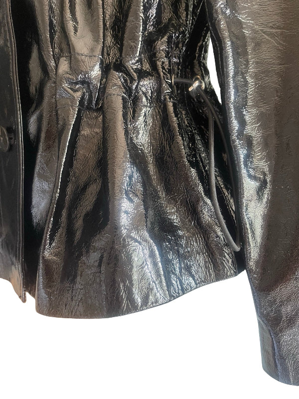 Close-up of a shiny black crinkled leather jacket with a drawstring waist and side pocket, shown against a white background.