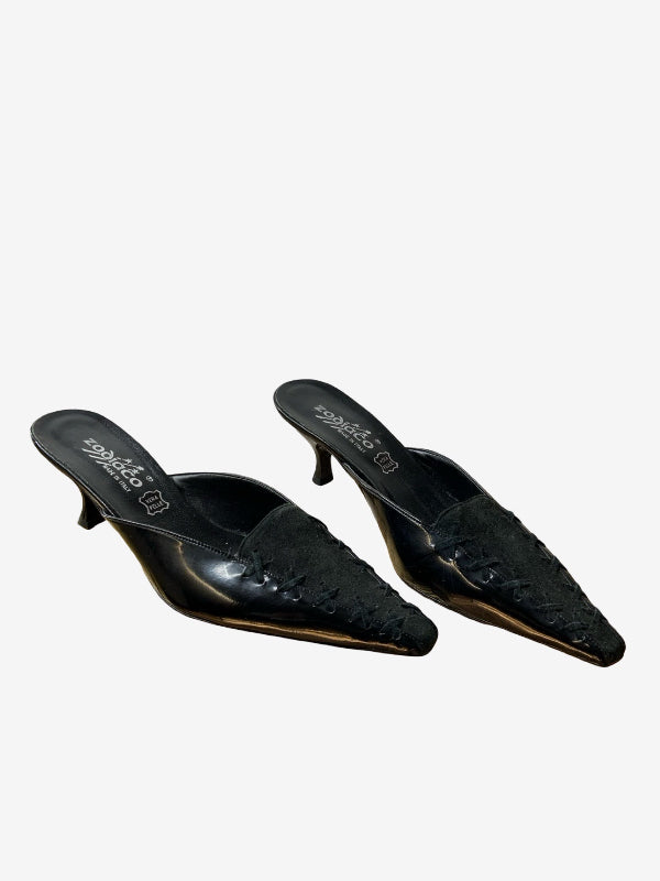 A pair of black pointed-toe mule heels with textured  leather detailing on the toe caps and a low kitten heel, shown against a plain light gray background.