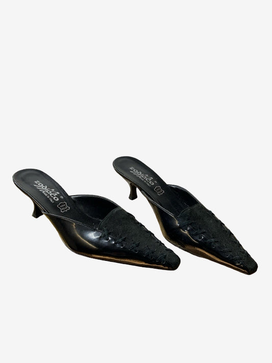 A pair of black pointed-toe mule heels with textured  leather detailing on the toe caps and a low kitten heel, shown against a plain light gray background.