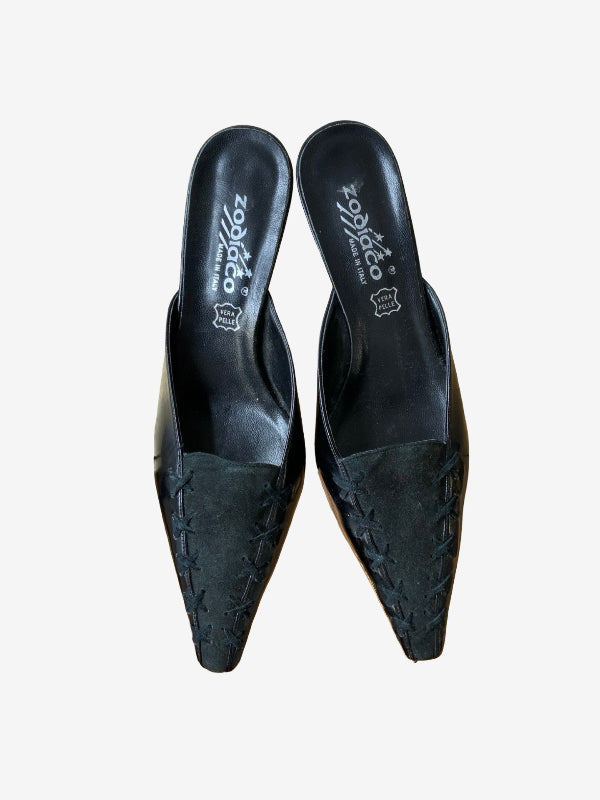 A pair of black pointed-toe mule heels with textured, embossed stitched detailing on the toes, shown from a top-down view on a light gray background. The brand name 'zodiaco' is printed on the insoles.