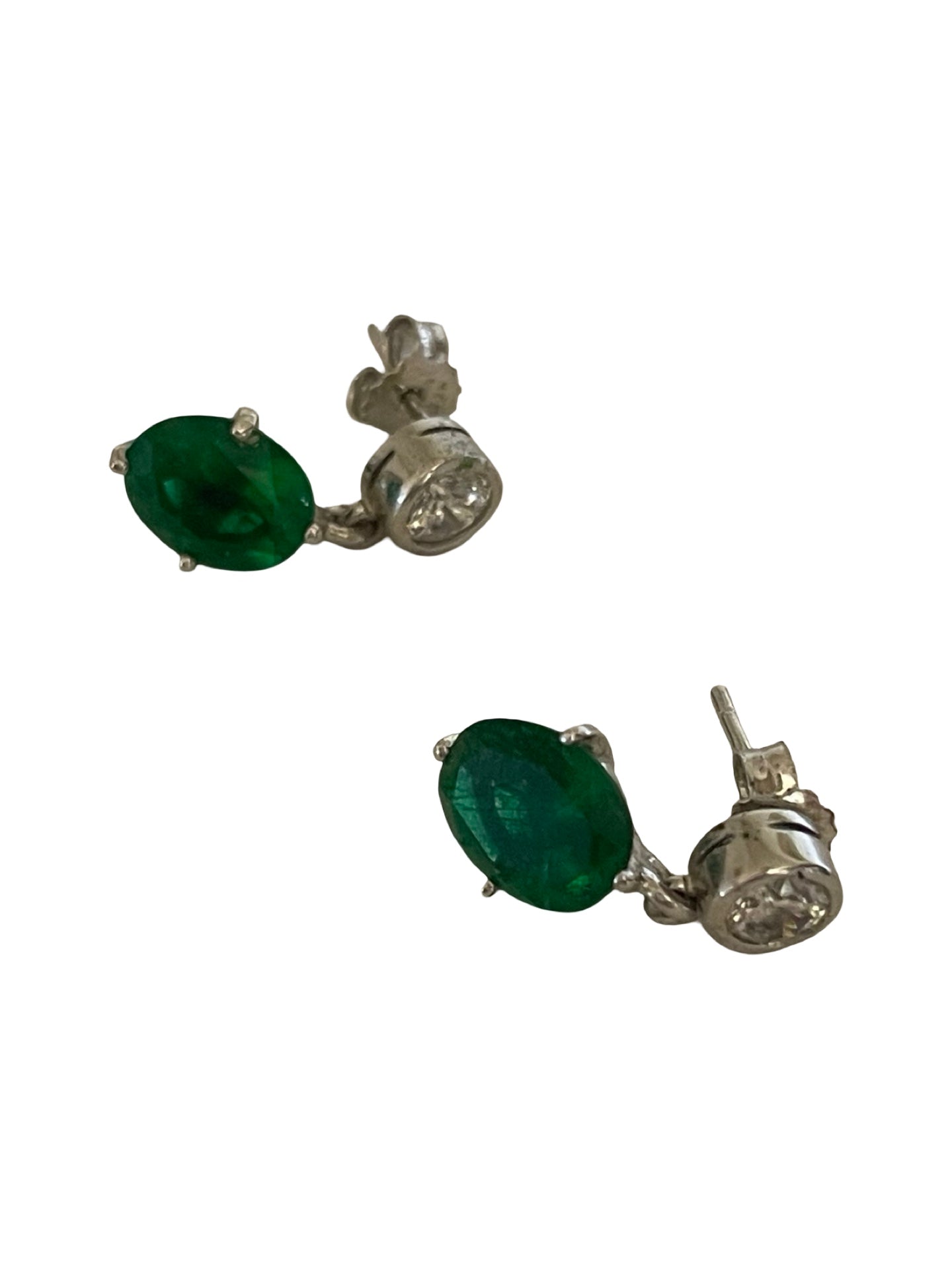 A pair of silver stud earrings featuring oval-cut green emerald-cut gemstones and a small round clear stone in each setting, shown against a plain white background.