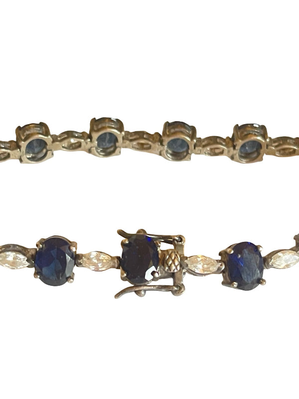 A vintage tennis bracelet featuring oval dark blue sapphires and marquise-cut clear crystals in a gold-toned setting, shown against a plain white background.