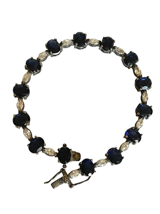 A vintage-style tennis bracelet featuring round dark blue cabochon gemstones and marquise-cut clear crystals set in silver-toned metal, shown against a plain white background.