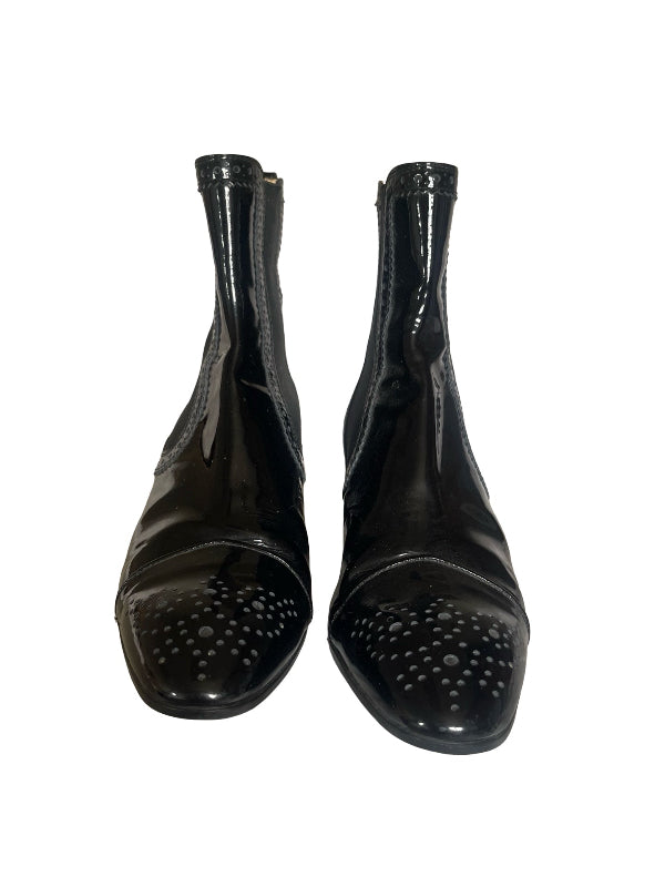 A pair of black patent leather ankle boots with perforated detailing on the toe caps, shown against a plain white background.