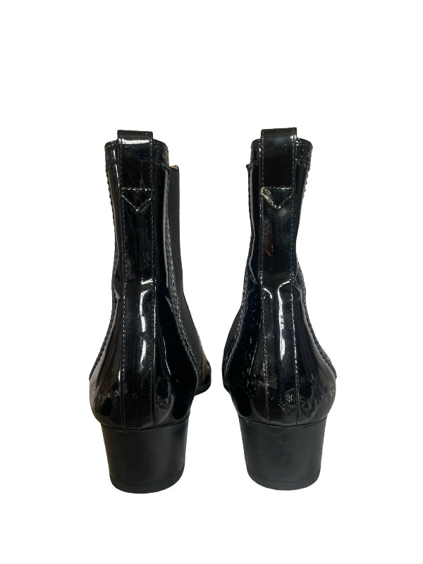 A pair of black patent leather ankle boots with a block heel, shown from the back against a plain white background.