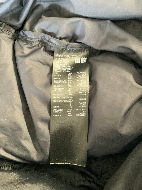 Close-up of a black garment label sewn onto the inside of a dark gray or black puffer jacket, showing the brand name 'UNIQLO' and care instructions.