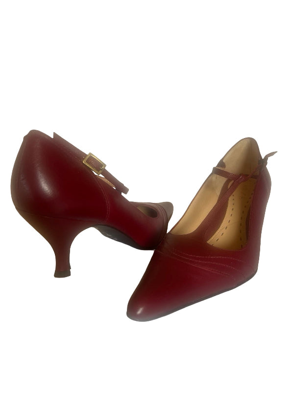 A pair of women's pointed-toe kitten heels in deep burgundy red leather, featuring a strap with a gold buckle on one shoe and a matching ankle strap on the other, set against a plain white background.