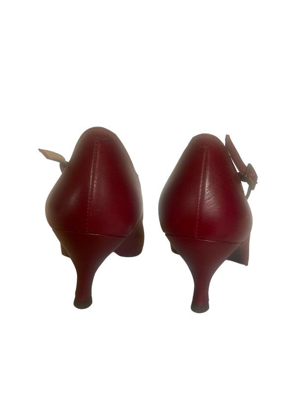 A pair of red leather kitten heel pumps shown from the back, featuring a small bow detail on the heel counter, set against a plain white background.