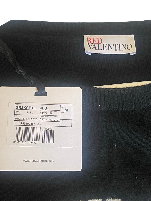 Close-up of a black knit sweater with a visible Valentino brand label and a white product tag showing size and barcode details.