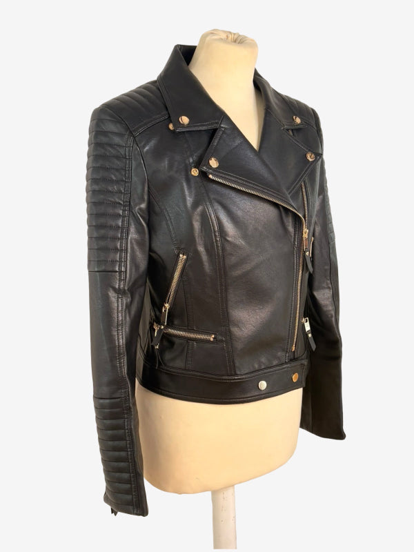 Black faux leather motorcycle jacket with gold-tone hardware, displayed on a beige mannequin torso against a light gray background.