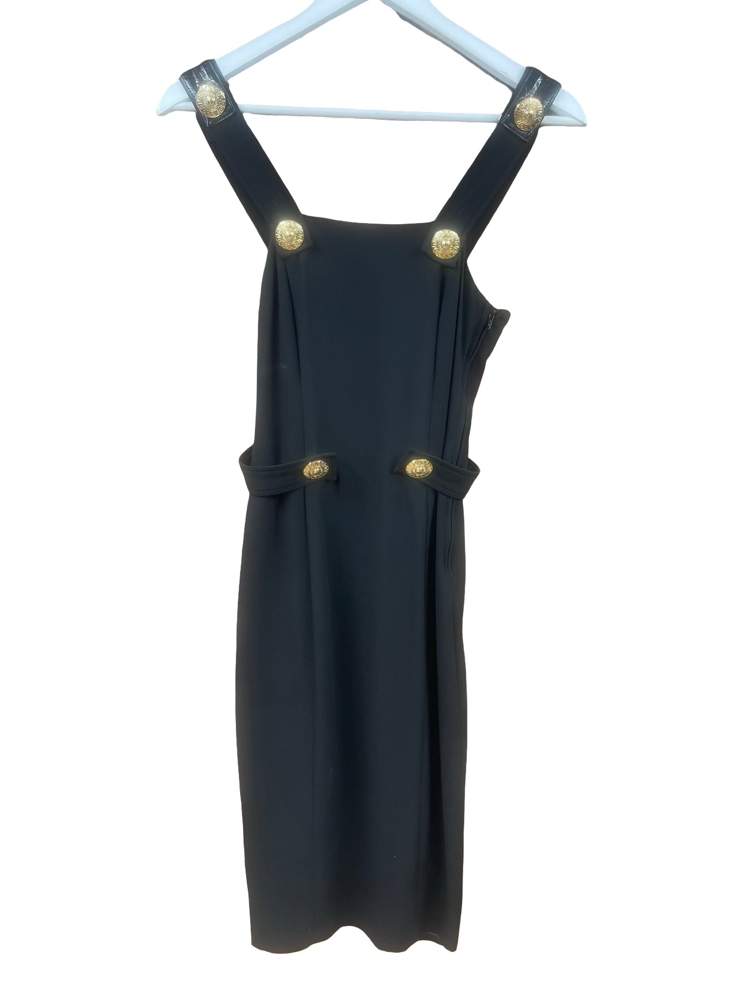 A black sleeveless dress with wide shoulder straps and gold-tone decorative buttons, hanging on a white hanger against a plain white background.