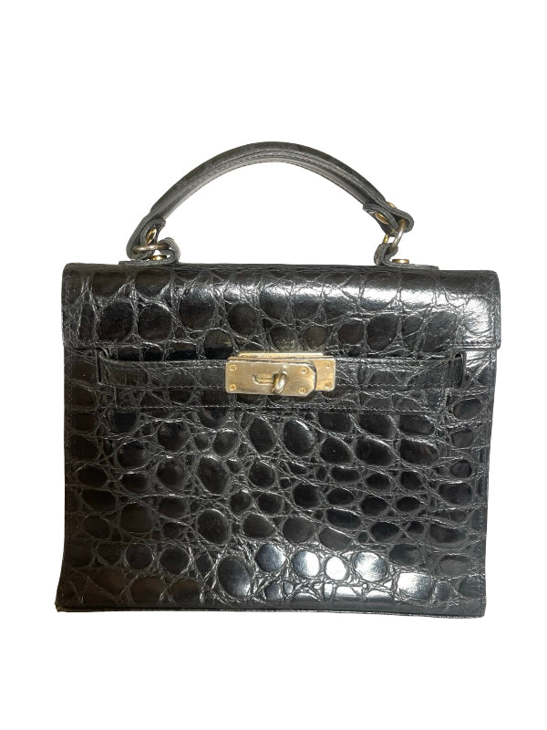 A black crocodile-embossed leather handbag with a top handle and a gold-tone turn-lock clasp, shown against a plain white background.