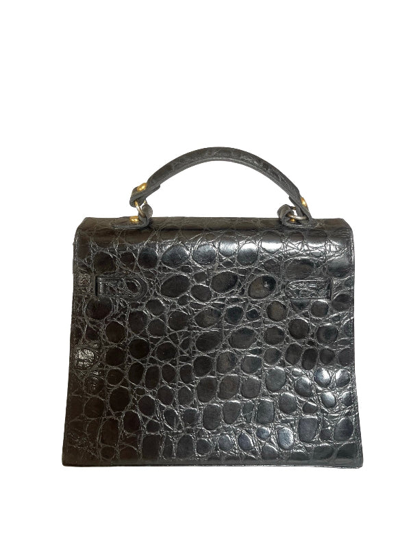 A structured black crocodile-embossed leather handbag with a top handle and gold-tone hardware, shown against a plain white background.