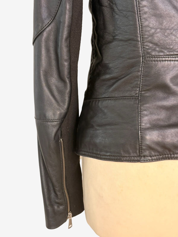 Close-up of a black leather jacket on a beige mannequin torso, showing the sleeve with a zip pocket and the back panel stitching.