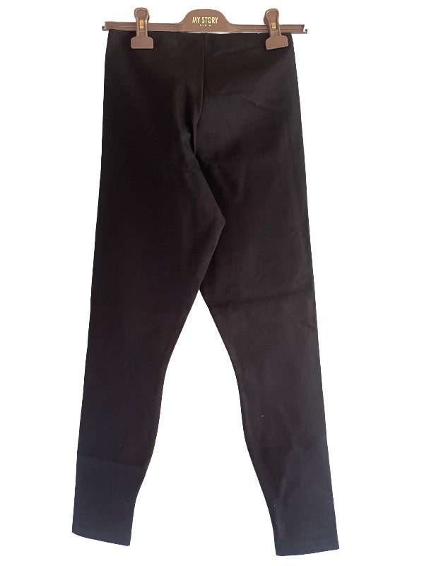 Black cropped leggings hanging from a brown wooden hanger, set against a plain white background.