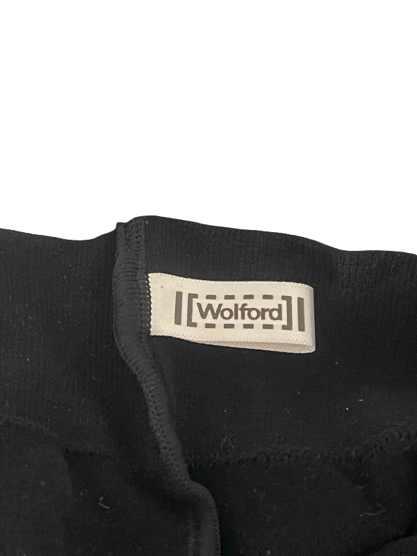 Close-up of a black knit garment with a cream fabric label reading 'Wolford' on a white background.